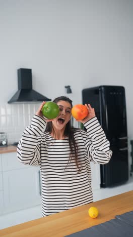 mujer jugando con frutas en la cocina