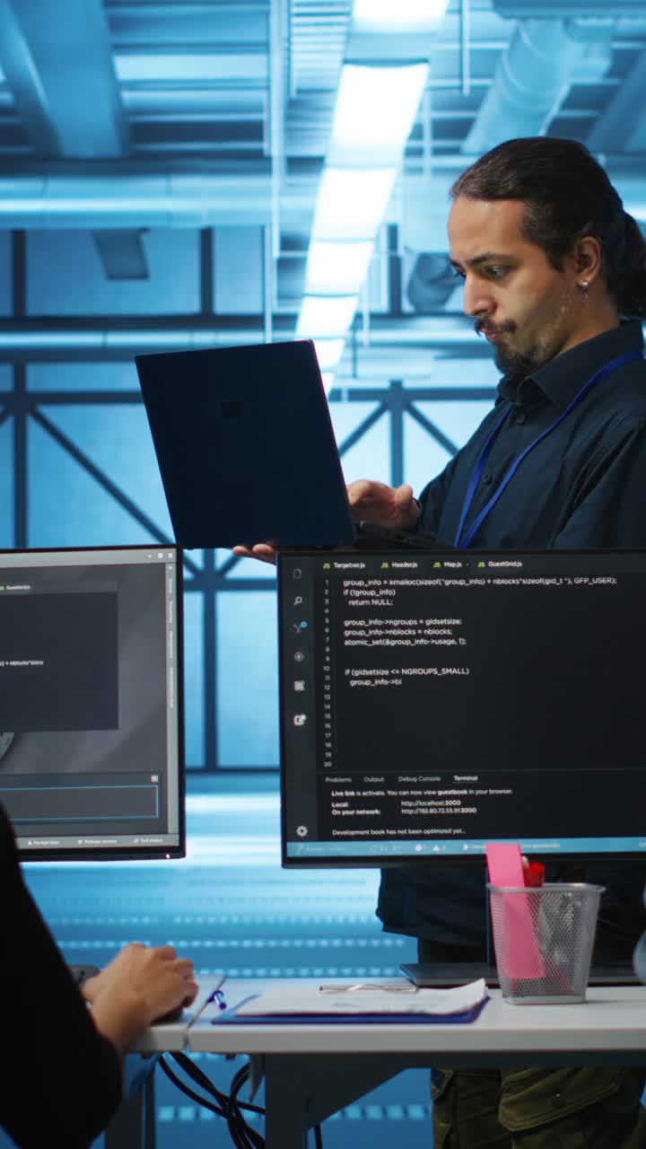 Mannlig programmerer som jobber på laptop og med kode i datasenterkontor