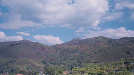 white clouds glide over a mountain landscape in a blue sky. time lapse shot.