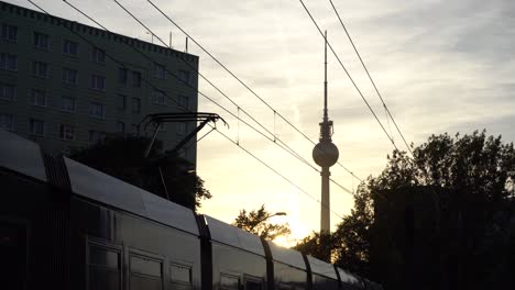 tram at railway station in berlin during lovely sunset with tv tower