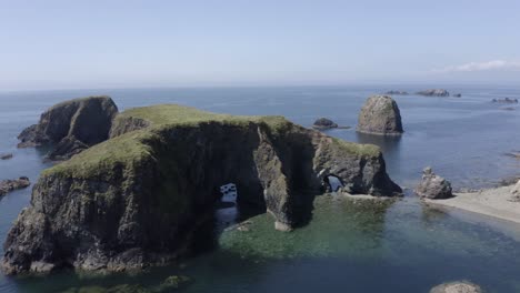 steep sided rock islet in the ocean has several eroded sea caves