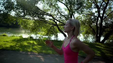 young caucasian woman jogging in public park near the river