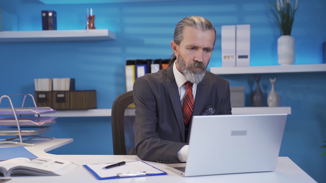 Voksen forretningsmand arbejder på bærbar computer ved bord på kontoret.
