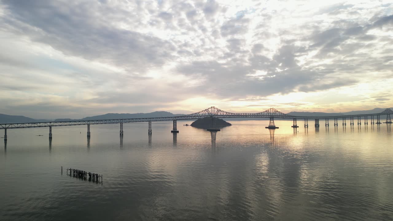 The Richmond–San Rafael Bridge appears in a wide aerial shot with the coastline of Point Molate Beach at sunset.