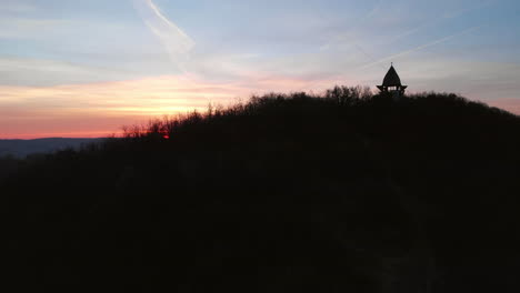 aerial zoom out of a viewpoint on a hill with sunrise in the background