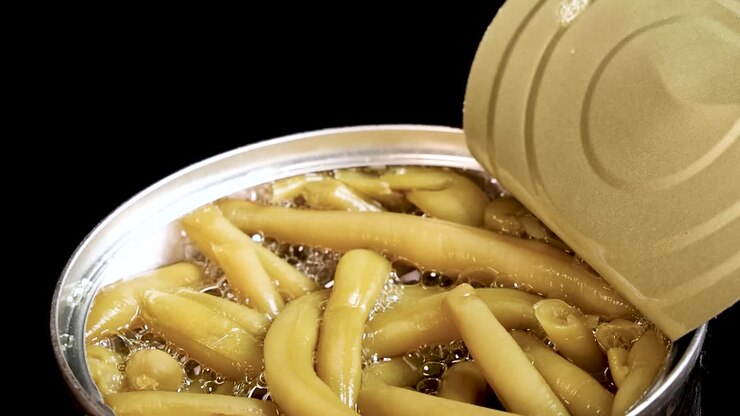 Macro shot of chopsticks picking up preserved haricot beans from an open metal can