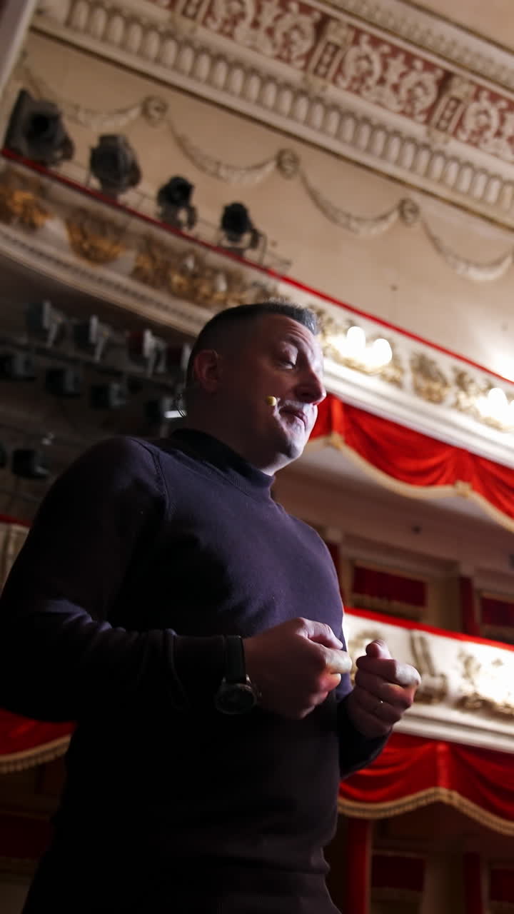 Actor man on a stage. Man wearing sweater performing on a scene in theatre. View from below. Vertical video