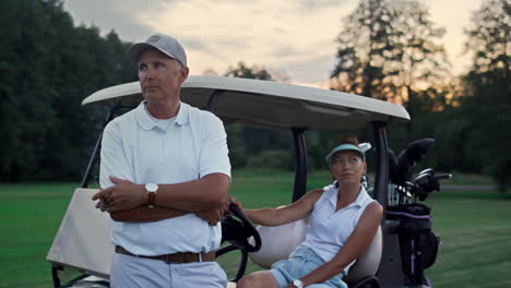Wealthy-golf-players-resting-at-golf-cart.-Sport-couple-enjoy-summer-weekend.