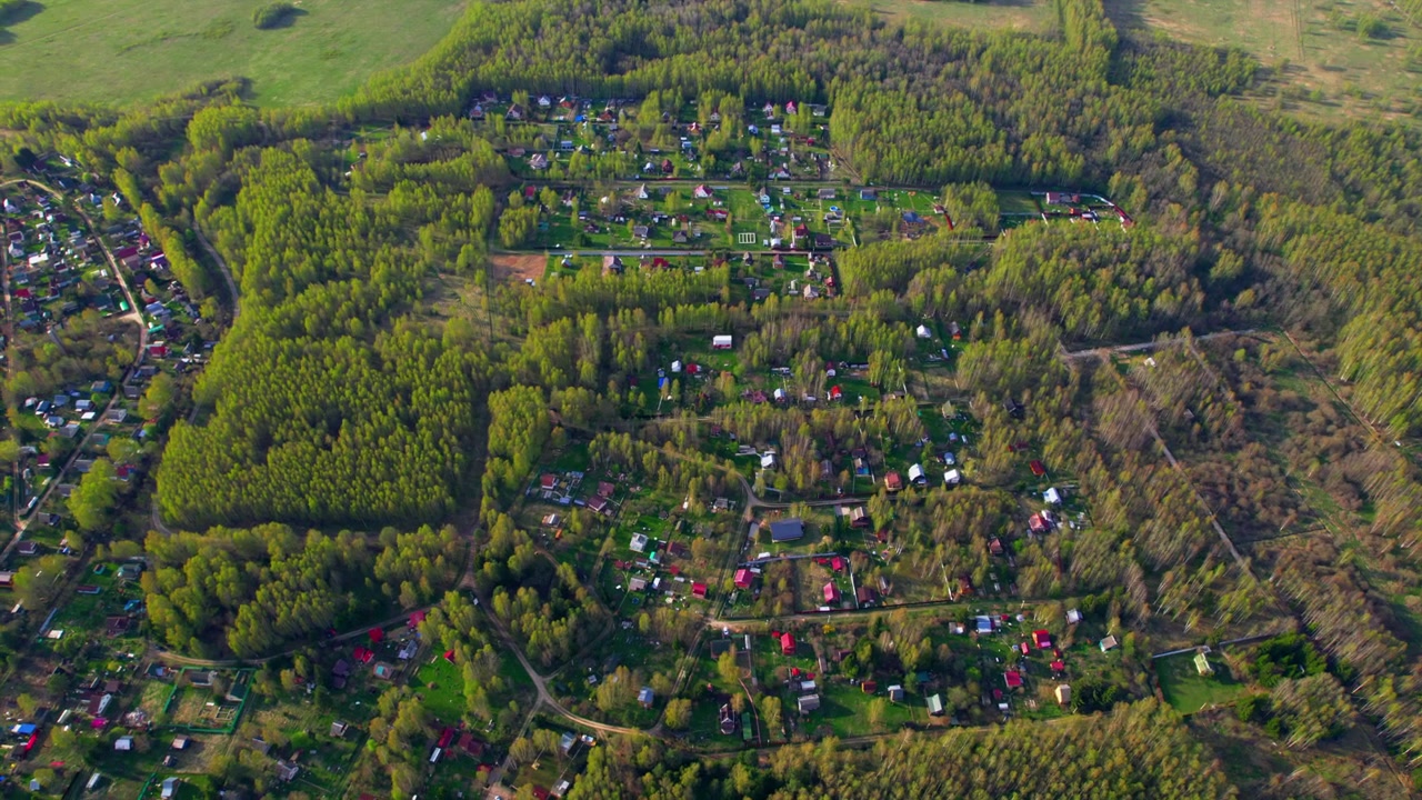 Aerial view green cottage village surrounded by spring forest and farmland edge for countryside living rural real estate nature travel and settlement pattern themes