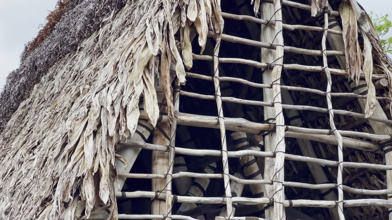 Cinematic close-up booming down shot an ancient Hawaiian thatched roof hale at Pu'uhonua O Honaunau National Historical Park in Hawai'i