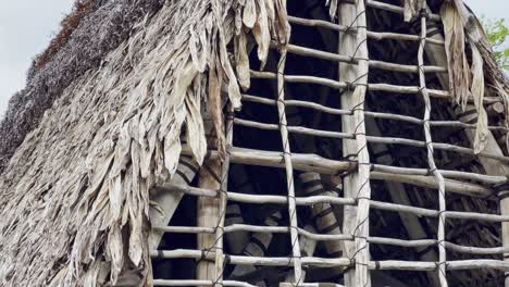 Cinematic close-up booming down shot an ancient Hawaiian thatched roof hale at Pu&#039;uhonua O Honaunau National Historical Park in Hawai&#039;i