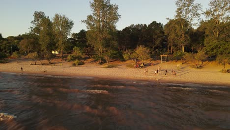 La-Costa-De-Fray-Bentos-En-Uruguay,-Donde-Un-Grupo-De-Amigos-Juegan-Voleibol-De-Playa-Al-Atardecer