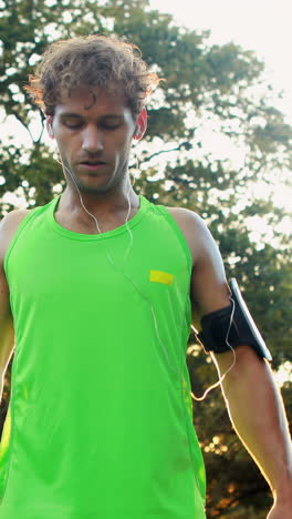 man adjusting music settings on armband from smartphone