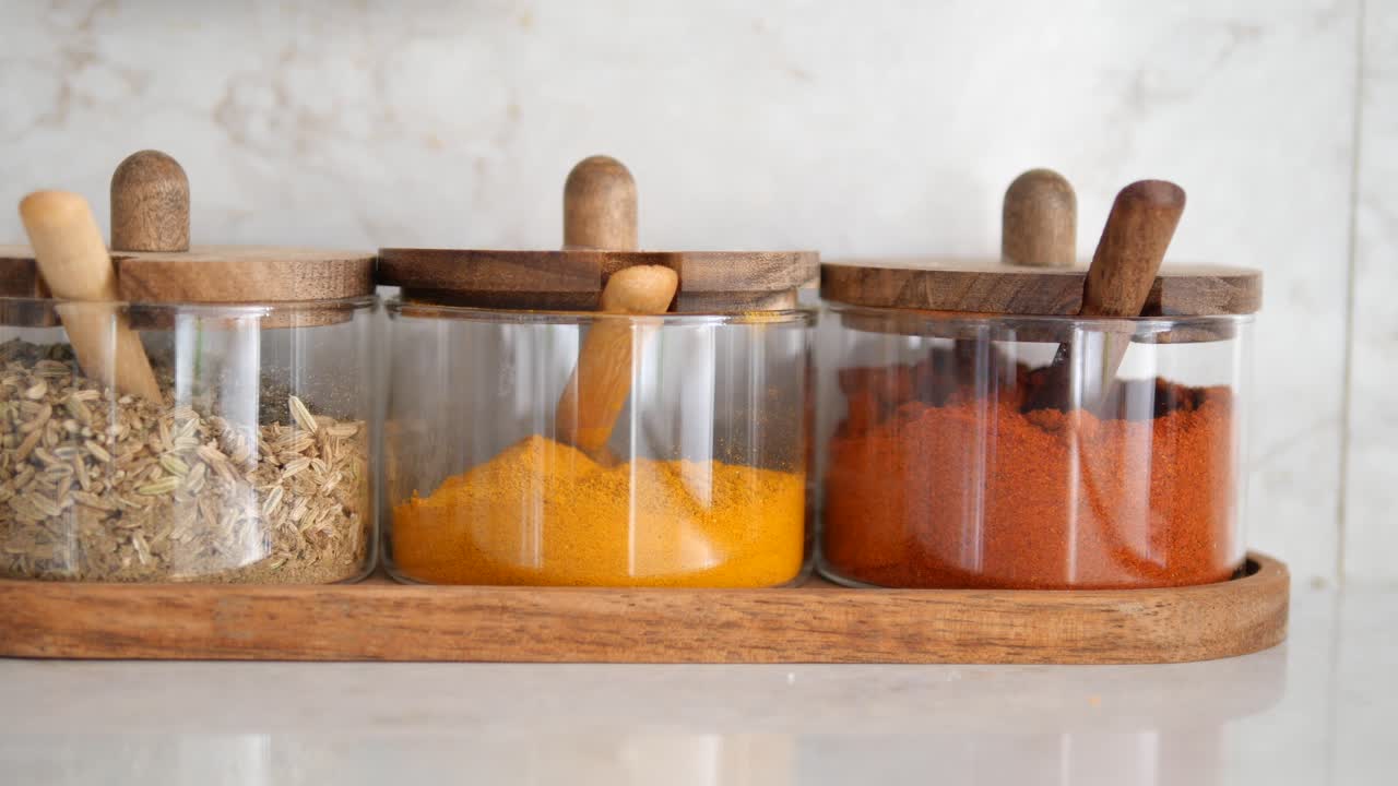 Varietà di spezie colorate in barattoli di vetro sul piano di lavoro della cucina