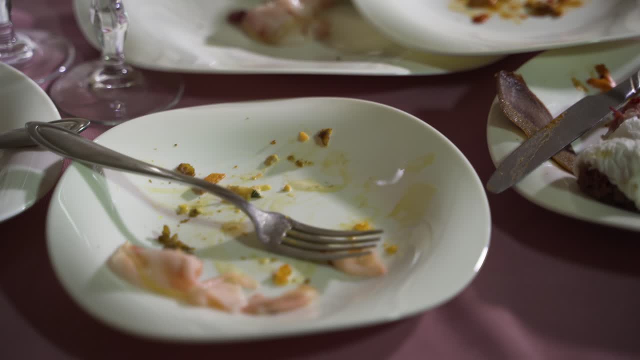 crumbs of dishes are on white plates on a pink background in the restaurant after the holiday. Leftovers