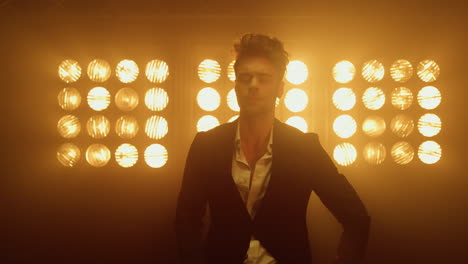 man model wearing suit buttoning jacket in club lights. guy posing in studio.