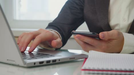 manos de mujeres con un teléfono inteligente y una computadora portátil