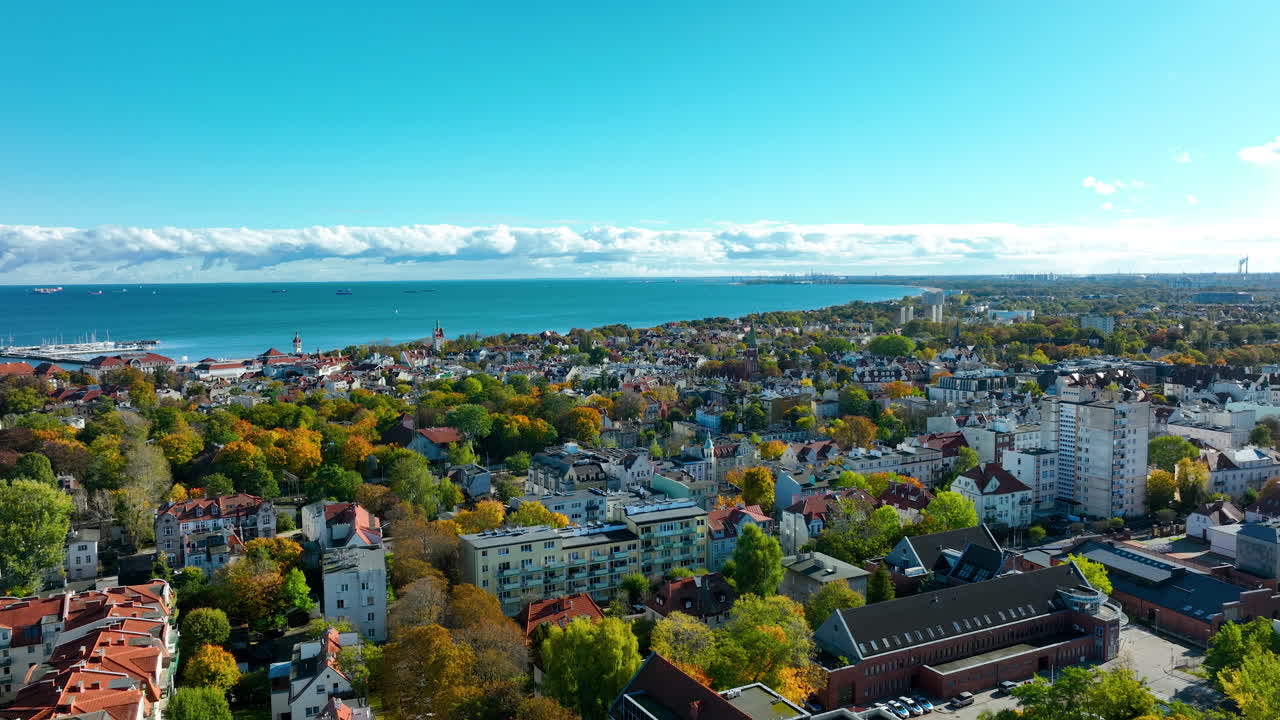 Drone panorama of Sopot city center with colorful rooftops, trees, and Baltic Sea coastline