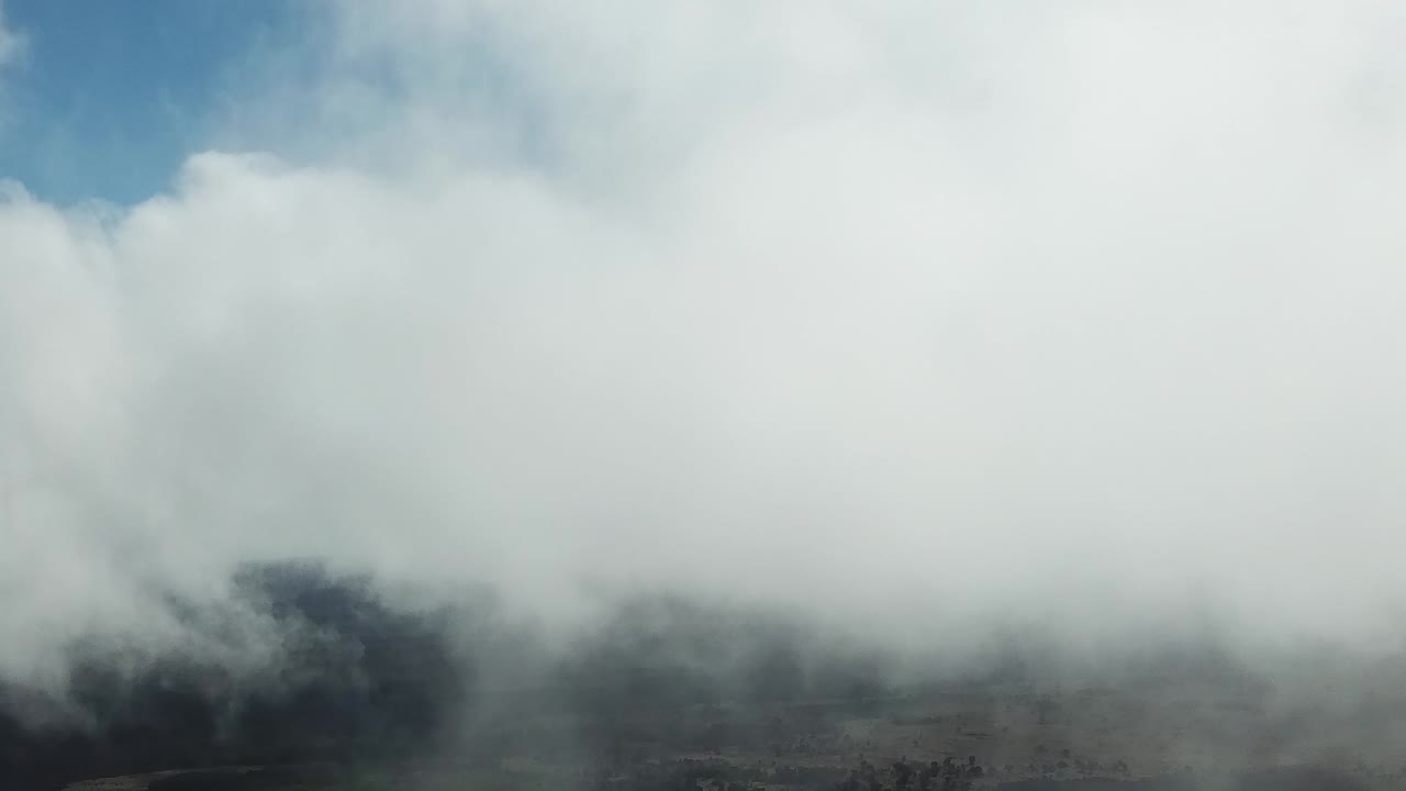 A dense cloud layer obscures the mountainous landscape below, creating a dramatic and mysterious atmosphere. Only faint outlines of the peaks are visible through the mist.