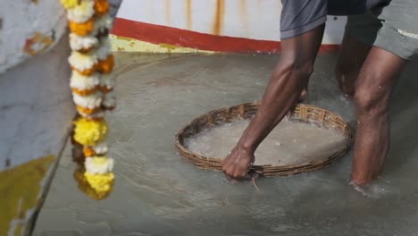 pescador indio enjuagando su captura de pescado y gambas en una cesta tejida con agua de mar a cámara lenta