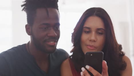 pareja feliz mirándose el uno al otro mientras usan un teléfono inteligente