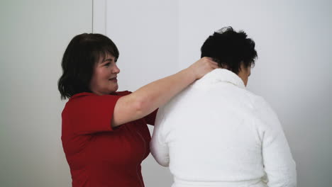 massage therapist examines shoulders of woman in clinic