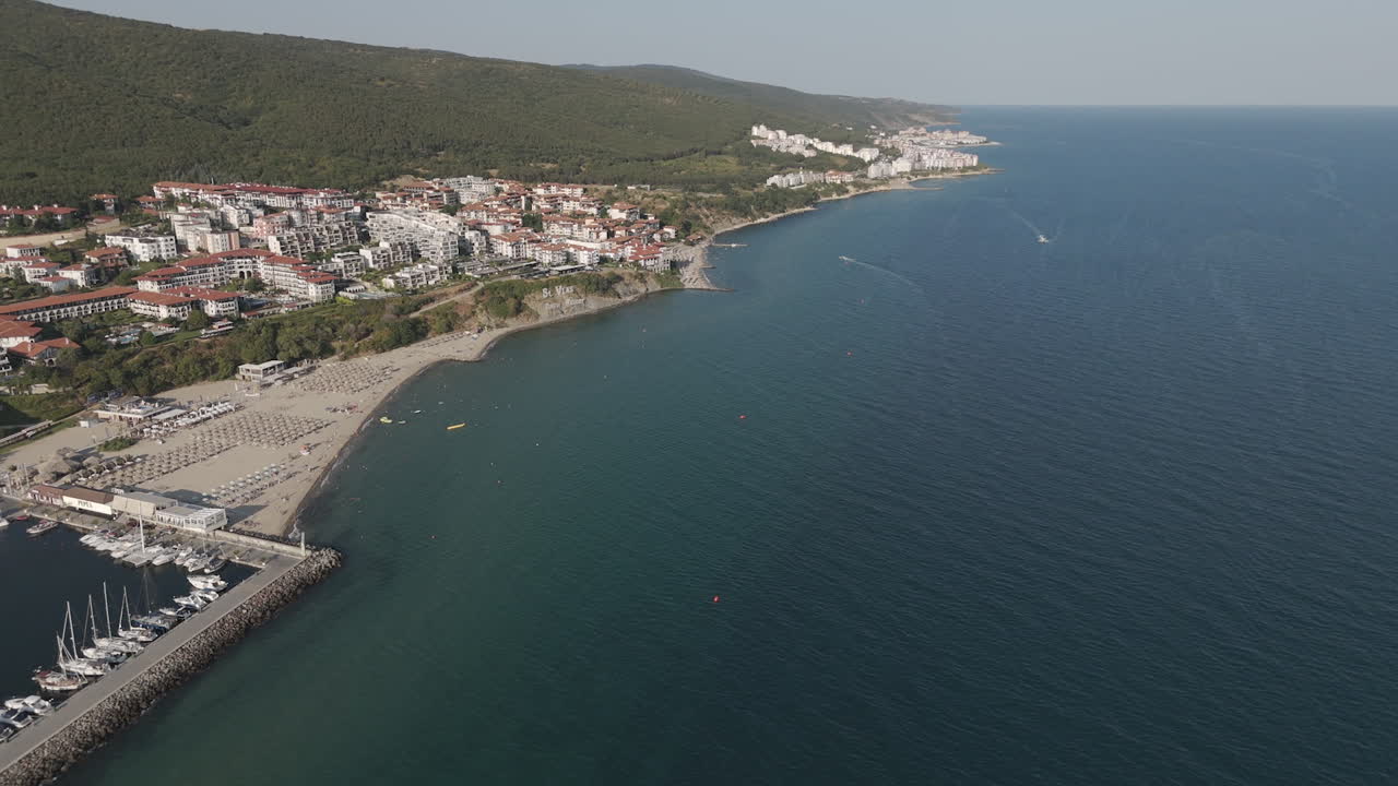 Coastal view of a beach town by the sea. Aerial view of a beach town with colorful buildings, sandy shores, and crystal-clear waters