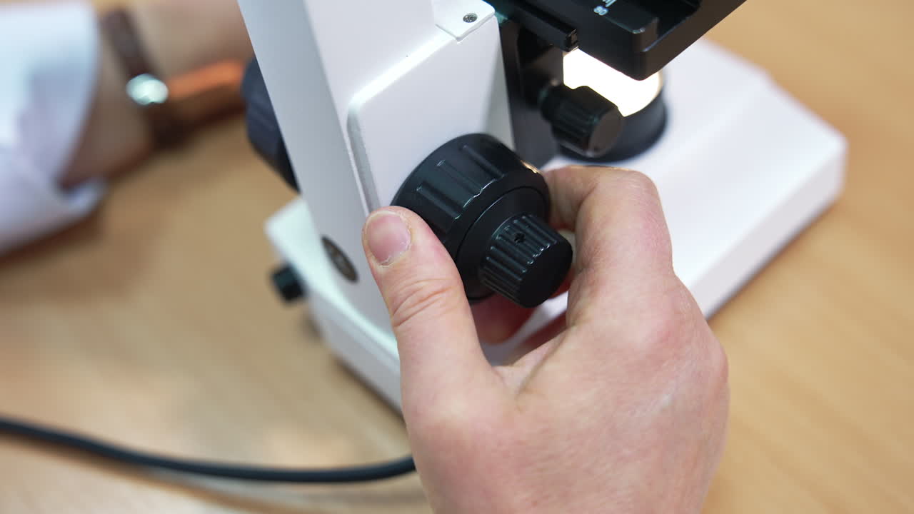 Adjusting microscope lenses into a necessary position. Laboratory research in medical care centre. Close up.