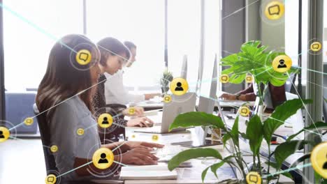 animation of network of digital icons over diverse team of colleagues working at office