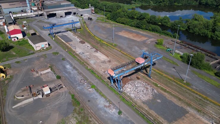 Gru a portale che trasporta rottami metallici presso le acciaierie elettriche di Hennigsdorf in una soleggiata giornata estiva. Inquadratura aerea unica realizzata con drone dall'alto