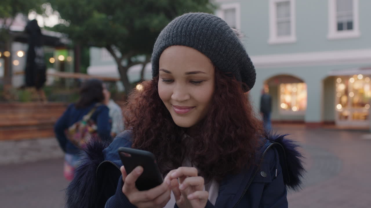 potrait of warmly dressed mixed race woman looking greeting using smartphone texting browsing social media