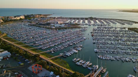la rochelle marina at golden hour, sailboats and yachts docked in harbor with atlantic ocean in background, france. aerial forward