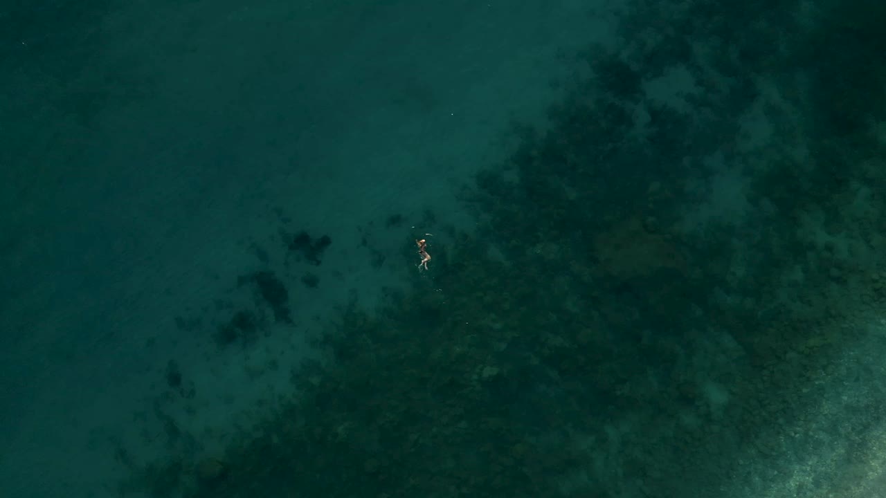 Ripresa dall'alto di una ragazza che nuota da sola in un bellissimo mare nel Mediterraneo