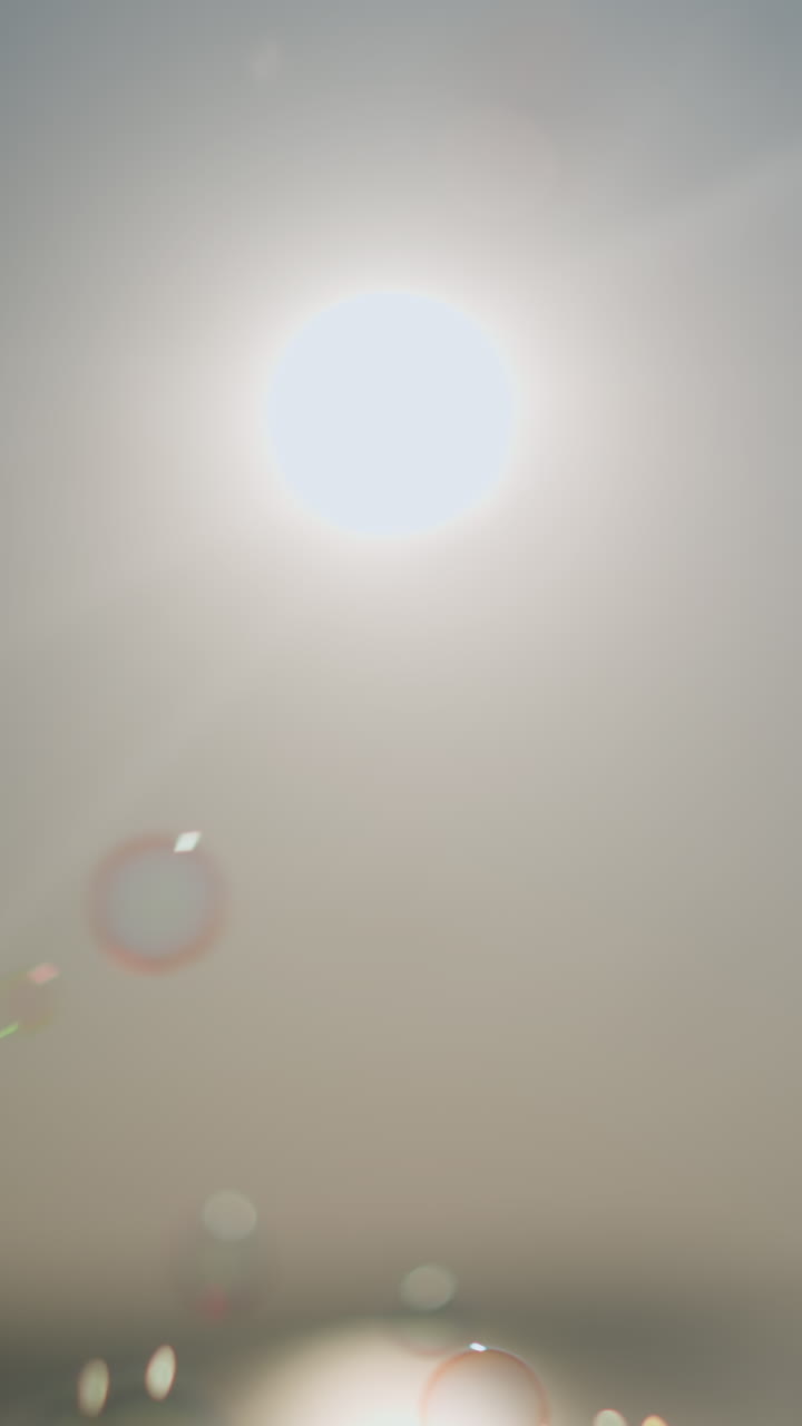 Close-up of colorful bubbles floating gracefully in the air under a bright sun, creating a dreamy, ethereal scene with light rays piercing through the bubbles, enhancing the magical atmosphere