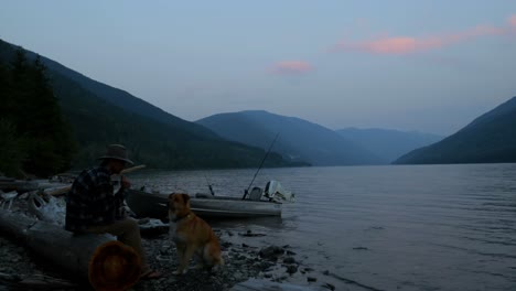 Fisherman-petting-his-dog-near-riverside-4k