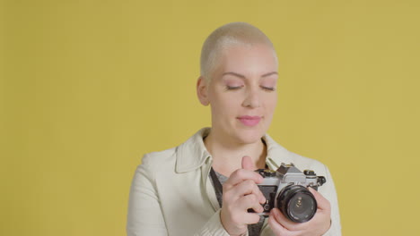 Female-caucasian-model-posing-with-vintage-SLR-against-yellow-backdrop-01