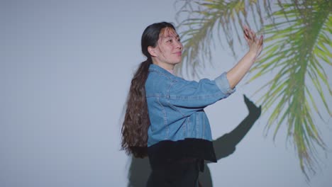 woman visiting and interacting with immersive art exhibition with images of palm leaves being projected onto her face 1