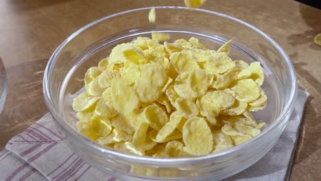 crispy yellow corn flakes into the bowl for the morning a delicious breakfast with milk. slow motion with rotation tracking shot.