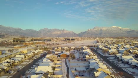 Idyllic-aerial-view-of-a-suburban-neighborhood-below-with-office-buildings,-a-highway-and-mountains-in-the-distance