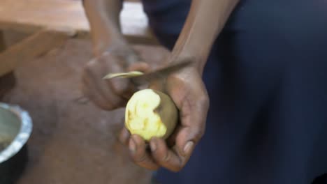 Close-up-top-down-shot-of-an-African-woman's-hand-peeling-potatoes-with-a-knife