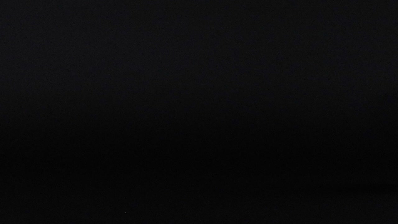 A green tennis ball moves dynamically against a dark backdrop, showcasing motion and contrast.