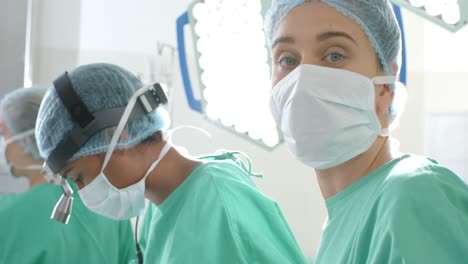 portrait of caucasian female surgeon wearing face mask in operating theatre, slow motion