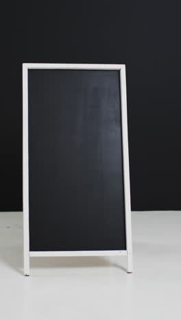 vertical video of blackboard sign on white stand with copy space on black background