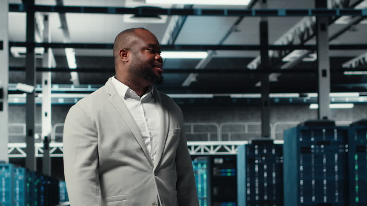 Vertical video Smiling engineer walking in data center, checking hardware for system stability