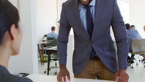 businessman and woman sitting at desk in an open plan office