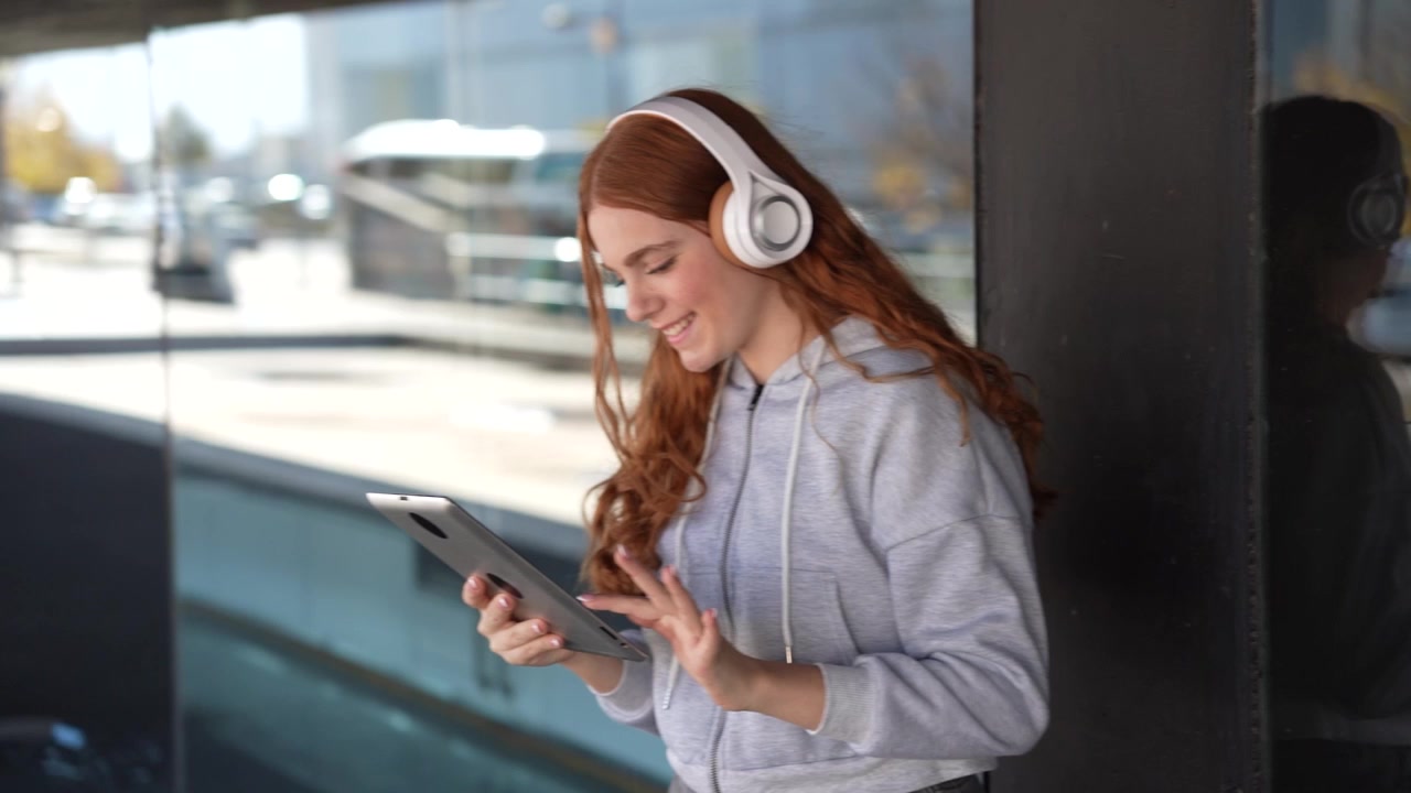 Una giovane donna si gode la musica mentre usa il suo tablet in un vivace ambiente urbano