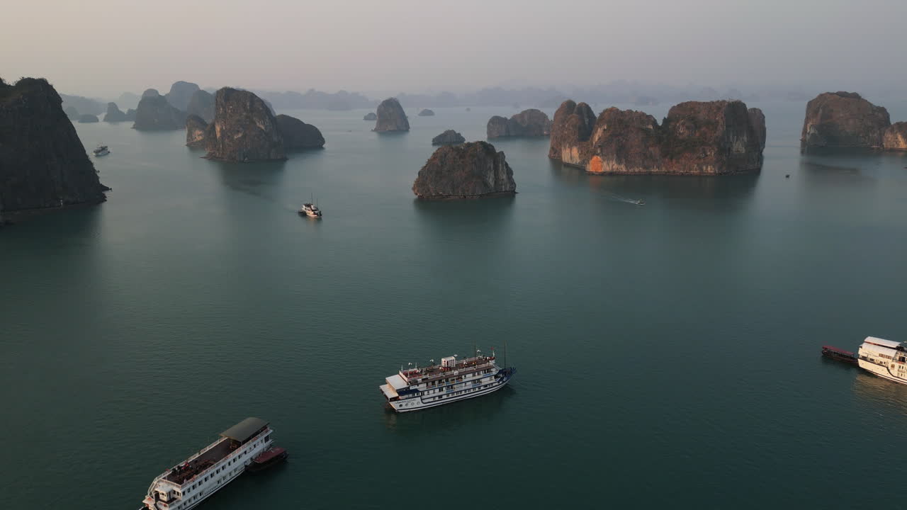 Aerial 4K drone footage over Ha Long Bay, Vietnam, showing tourist boats navigating among limestone karsts and emerald waters