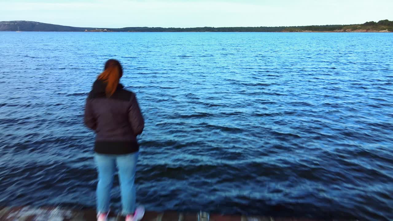 fpv drone volando por un viejo embarcadero de piedra pasando a una persona de espaldas