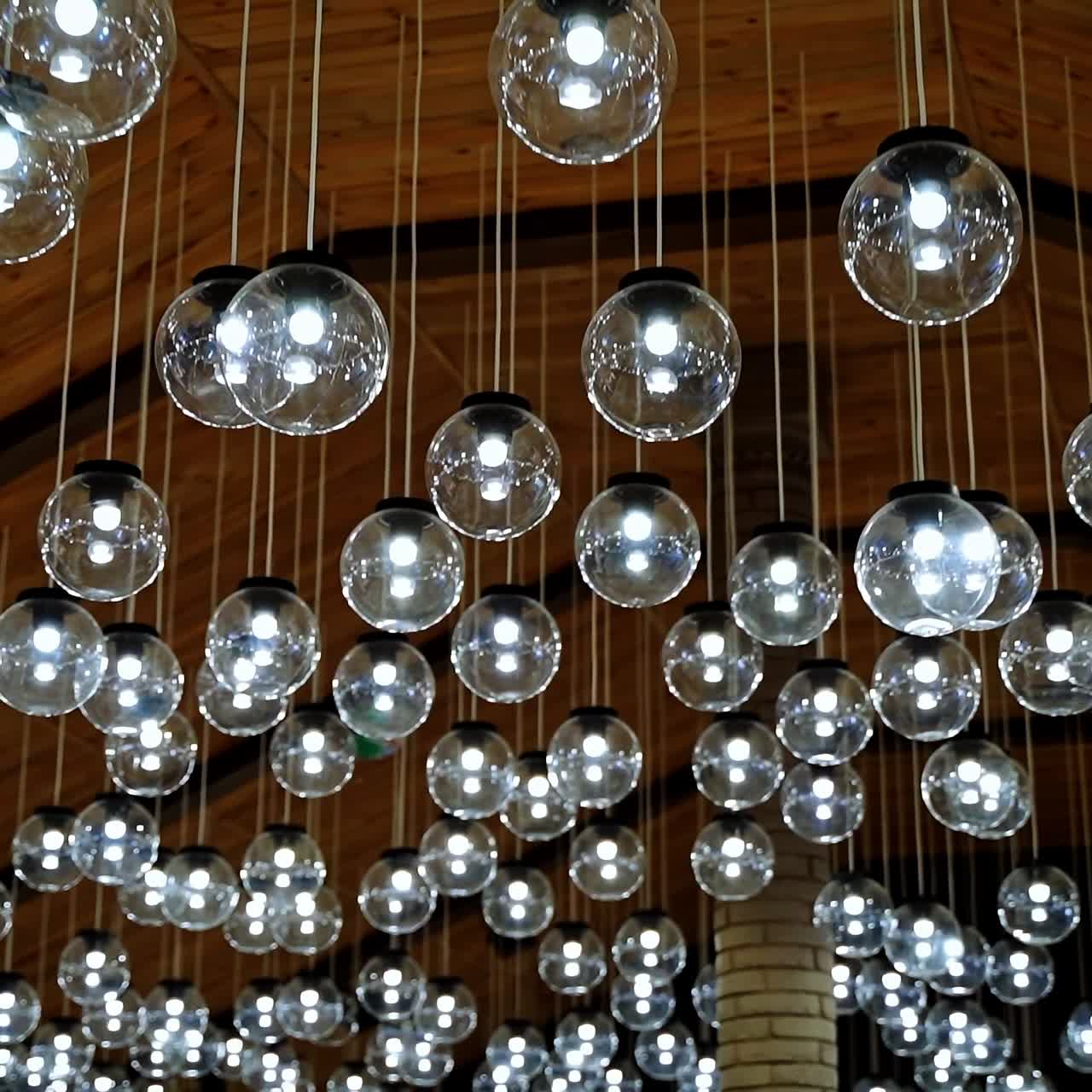 Many round light bulbs background. Beautiful ceiling with shining glass balls hanging on long white wires. Glamour ceiling.