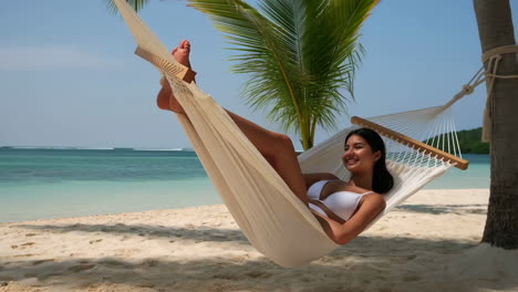 woman relaxing in hammock on tropical beach